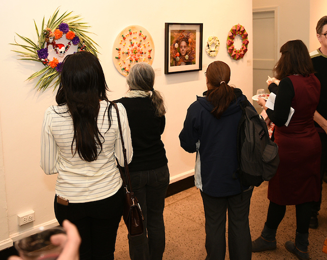 A crowd of people gathered around art displayed on a wall.