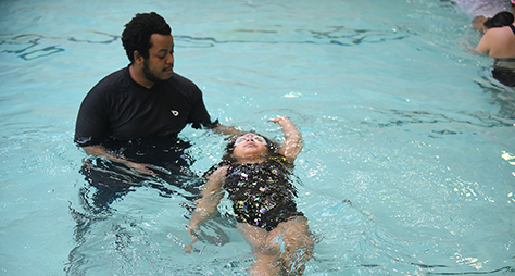 An instructor teaching a girl to swim.