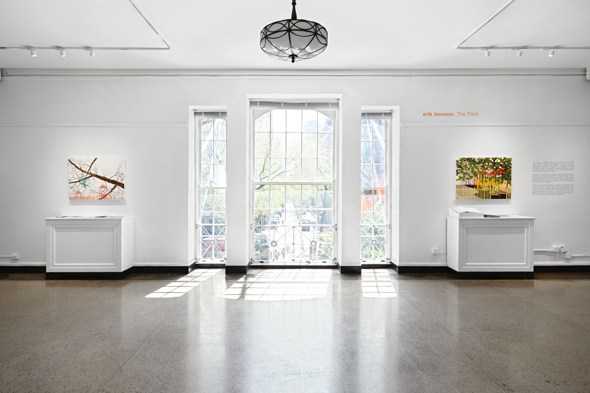 An empty, sunny view of the Arsenal Gallery. A large window lets in plenty of sunlight.