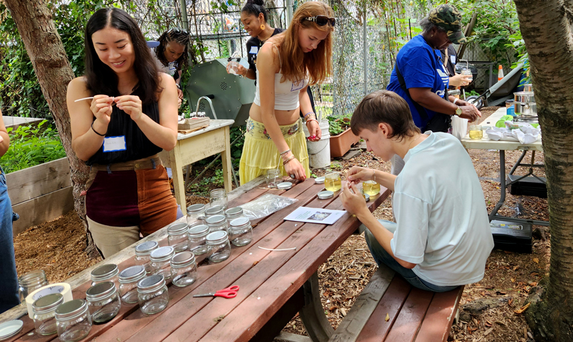 Attendees work on making candles at a candle making event hosted in a community garden.