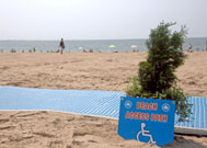 Sign on beach next to beach mat reads Beach Access Path