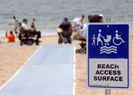 Sign on beach next to beach mat reads Beach Access Surface