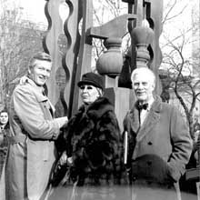 2 men and 1 women in front of a statue